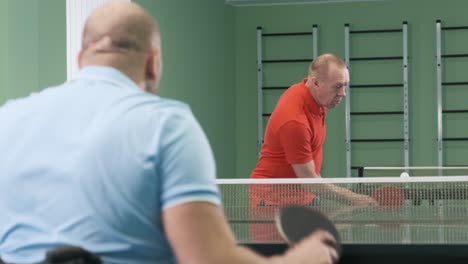 a man in a wheelchair plays ping pong. people with disabilities play table tennis. rehabilitation of the disabled. paralympic sport.