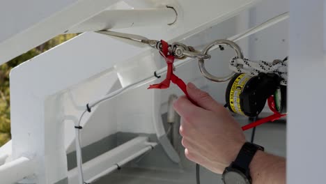 Ships-crew-checking-liferaft-release-mechanism,-close-up