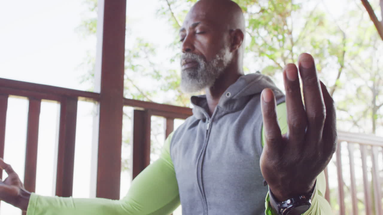 Senior African American man enjoys yoga in a log cabin, meditating in slow motion