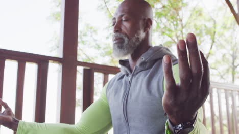 senior african american man enjoys yoga in a log cabin, meditating in slow motion