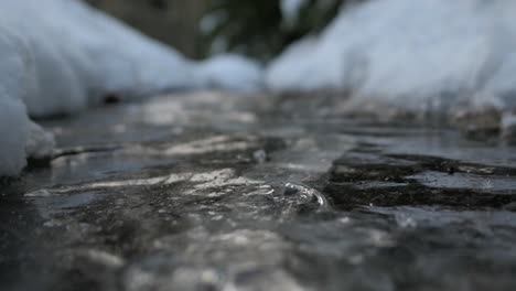 Wasser-Strömt-Unter-Eis,-Gefrorene-Bachluftblasen-Fließen-Unter-Eis