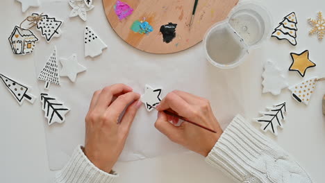 woman hand paints christmas ornaments with star shape