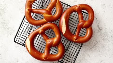 three german fresh baked pretzel buns placed on steel grill frame