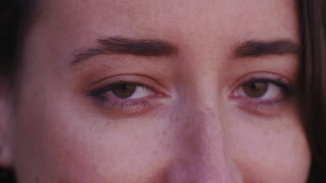 Close-up-portrait-of-a-glamorous,-young,-brown-eyed-woman-smiling-as-she-turns-to-look-into-the-camera