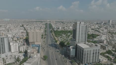 aerial drone shot from right to left of heavy traffic movement over shahrah e qaideen road, karachi metropolitan city, pakistan on a sunny day