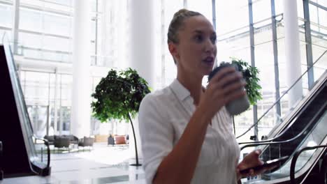 mujer de negocios usando teléfono móvil y caminando en el vestíbulo en la oficina 4k