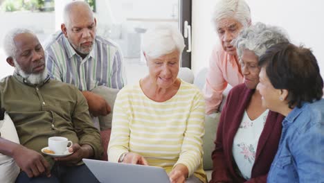 Happy-senior-diverse-people-talking-and-using-laptop-at-retirement-home