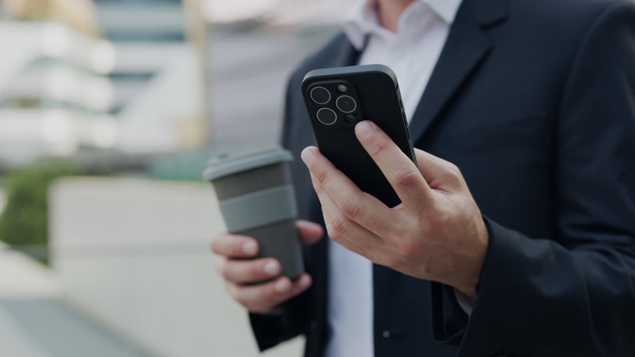 Businessman using smartphone and holding coffee