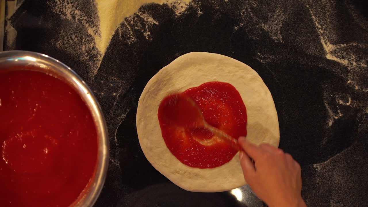 vista aérea de arriba hacia abajo de un cocinero profesional haciendo pizza italiana tradicional con queso parmesano, albahaca fresca, aceite de oliva y salsa de tomate