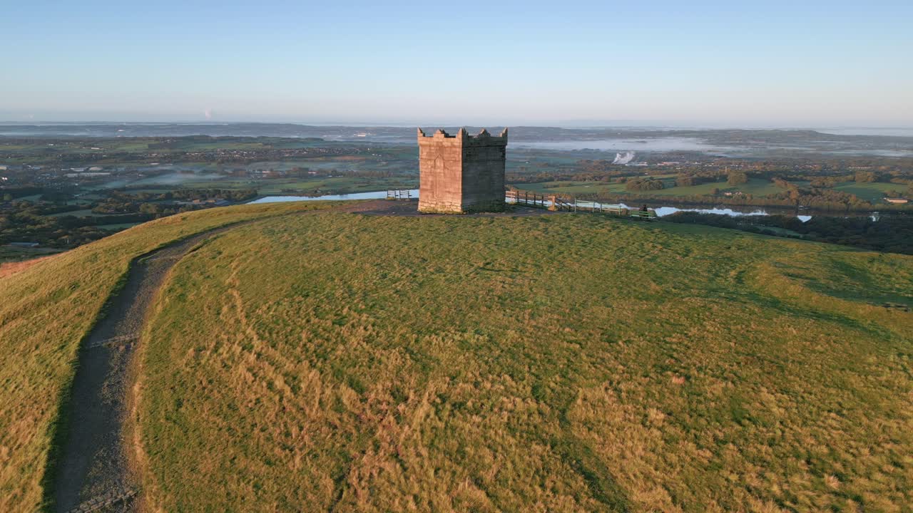 каменная башня на вершине холма с дорожкой, ведущей к ней и медленно подниматься во время рассвета осенью с раскрытием водохранилищ