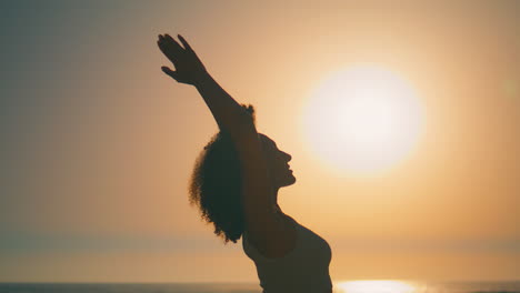 Silhouette-Einer-Frau,-Die-Am-Strand-Bei-Sonnenaufgang-Die-Hände-Zum-Himmel-Hebt,-Nahaufnahme.-Mädchenmeditation