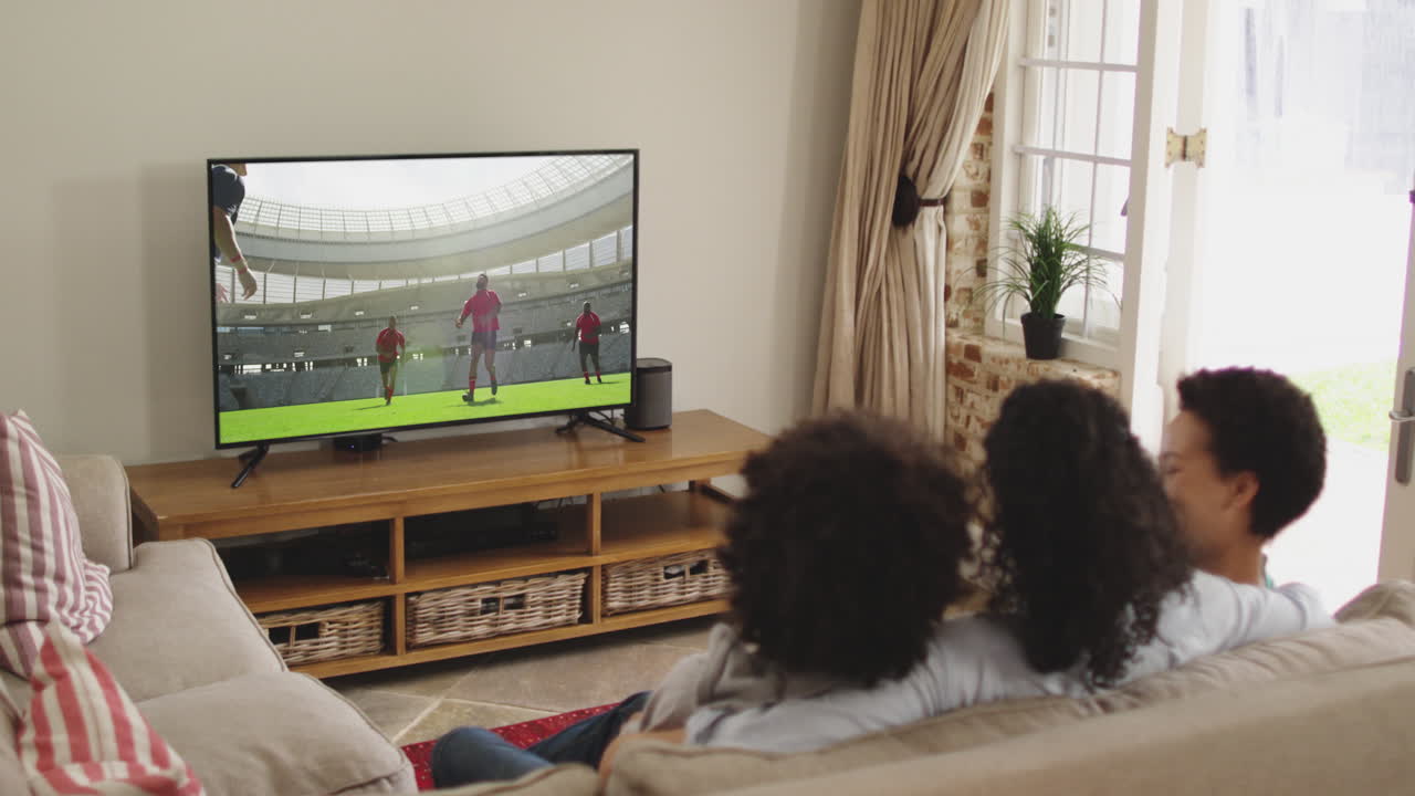 Famiglia felice seduta a casa insieme che guarda una partita di rugby in TV