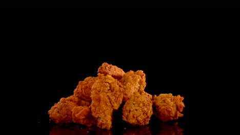 golden, crispy fried chicken pieces are shown in a slow motion zoom, with dramatic lighting and a black background emphasizing texture and color