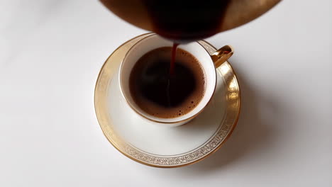 pouring coffee into an elegant white and gold cup