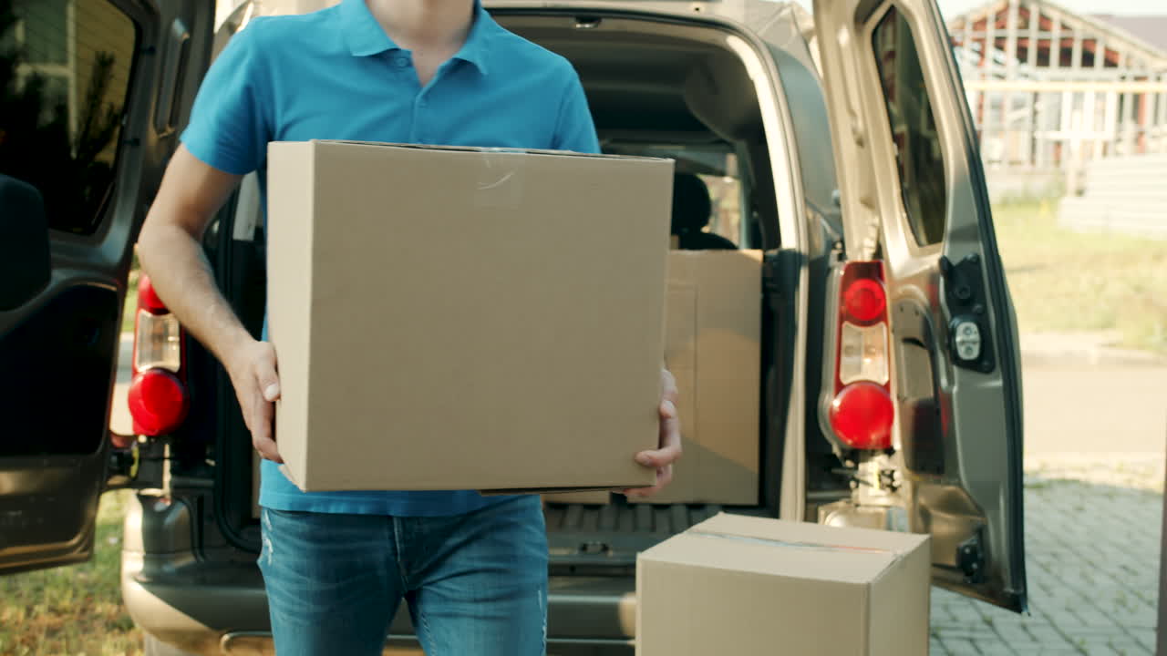 Man holding cardboard box by moving truck