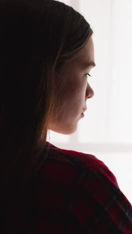 elegant young woman stands near large window in room backside view slow motion. dreaming lady spends time alone at home. unhappy mental state