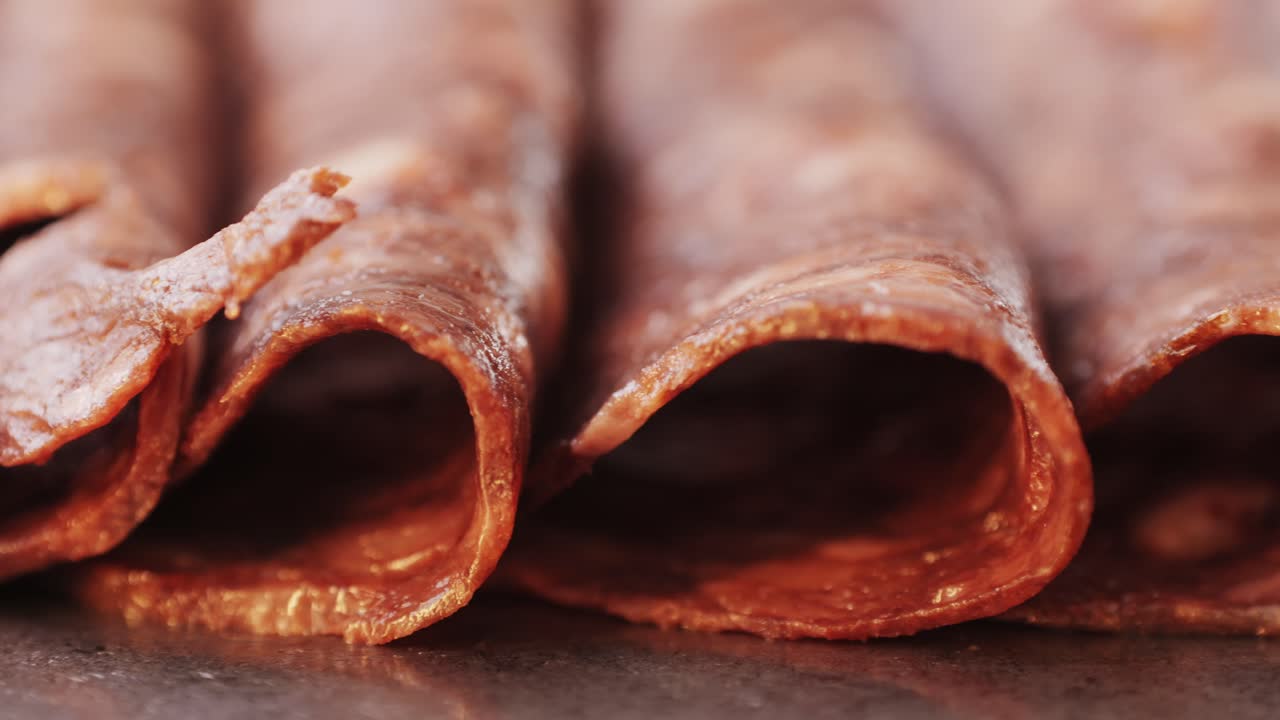black bull sausage ham, tongue pork dry-cured sausage on a black background, traditional spanish delicatessen food, close up.