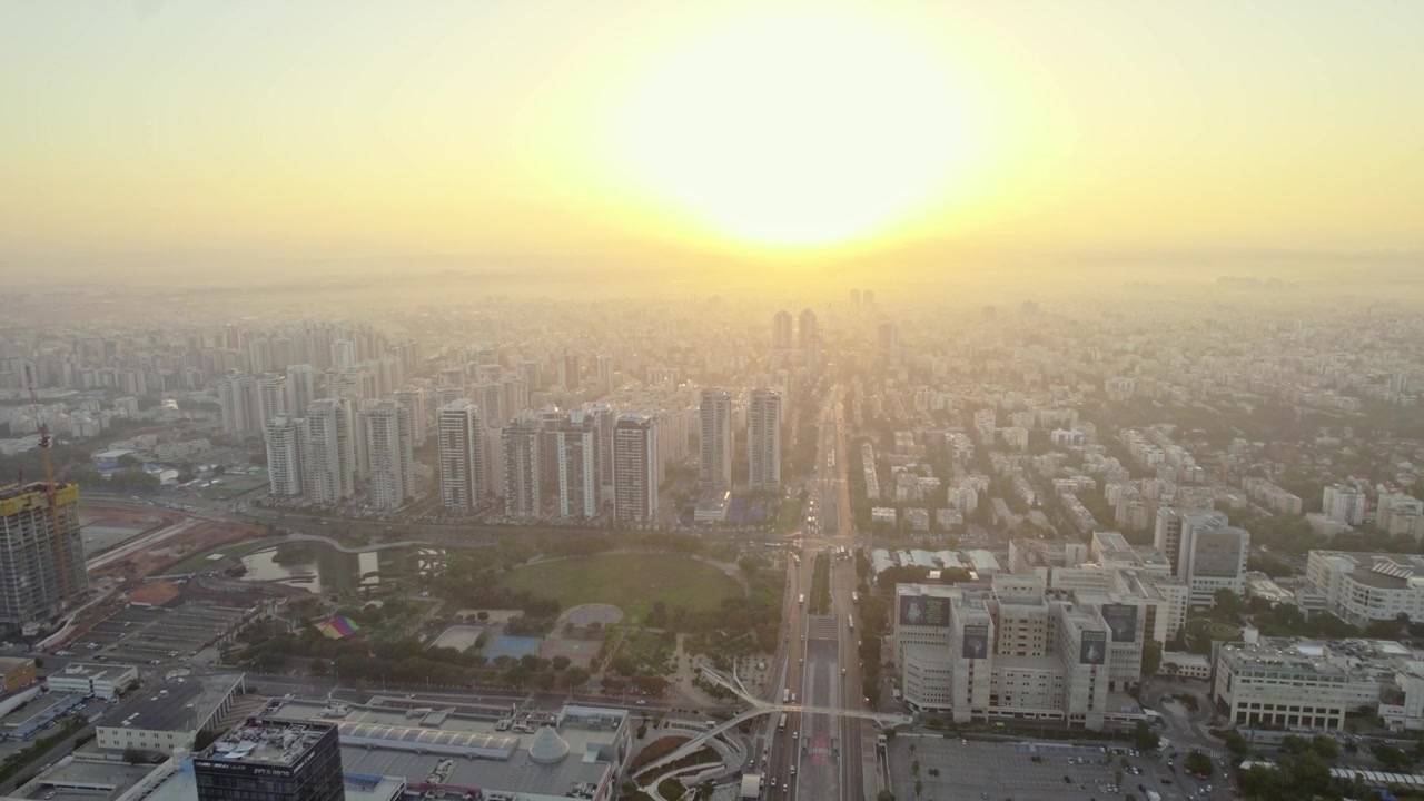 Panorama aéreo de alta altitude do horizonte da cidade de Petah Tikva sob um nascer do sol dourado e nebuloso.