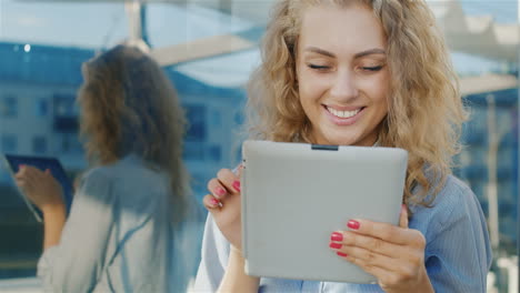 portrait of an attractive young woman uses tablet near the mirror wall positive emotions