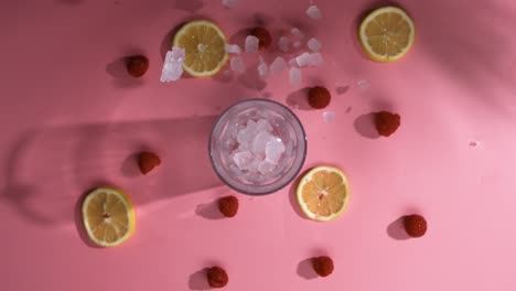 cubitos de hielo cayendo sobre la mesa de frutas con vaso de cóctel