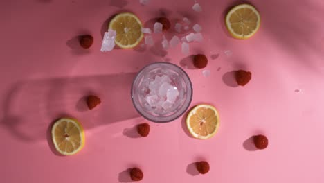 cubitos de hielo cayendo sobre la mesa de frutas con vaso de cóctel