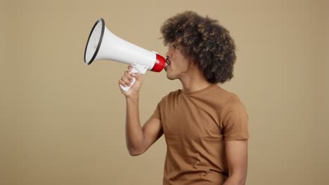 young man with an afro hairstyle shouting and speaking into a megaphone