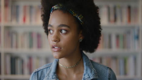 Retrato-Hermosa-Joven-Afroamericana-Estudiante-Mirando-Alrededor-Pensativa-Contemplativa-Sonriendo-Feliz-Con-Peinado-Afro-Cámara-Lenta-Fondo-De-Estantería