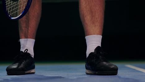 tennis player holding the ball and getting ready to serve. close-up feet tennis player preparing to serve. knocking the ball on the court and hitting the racket