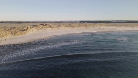 Exotic-sandy-beach-with-rocky-cliffs-and-ocean-waves-hitting-coast,-aerial-view