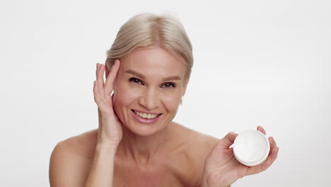 mature woman smiling with skincare cream