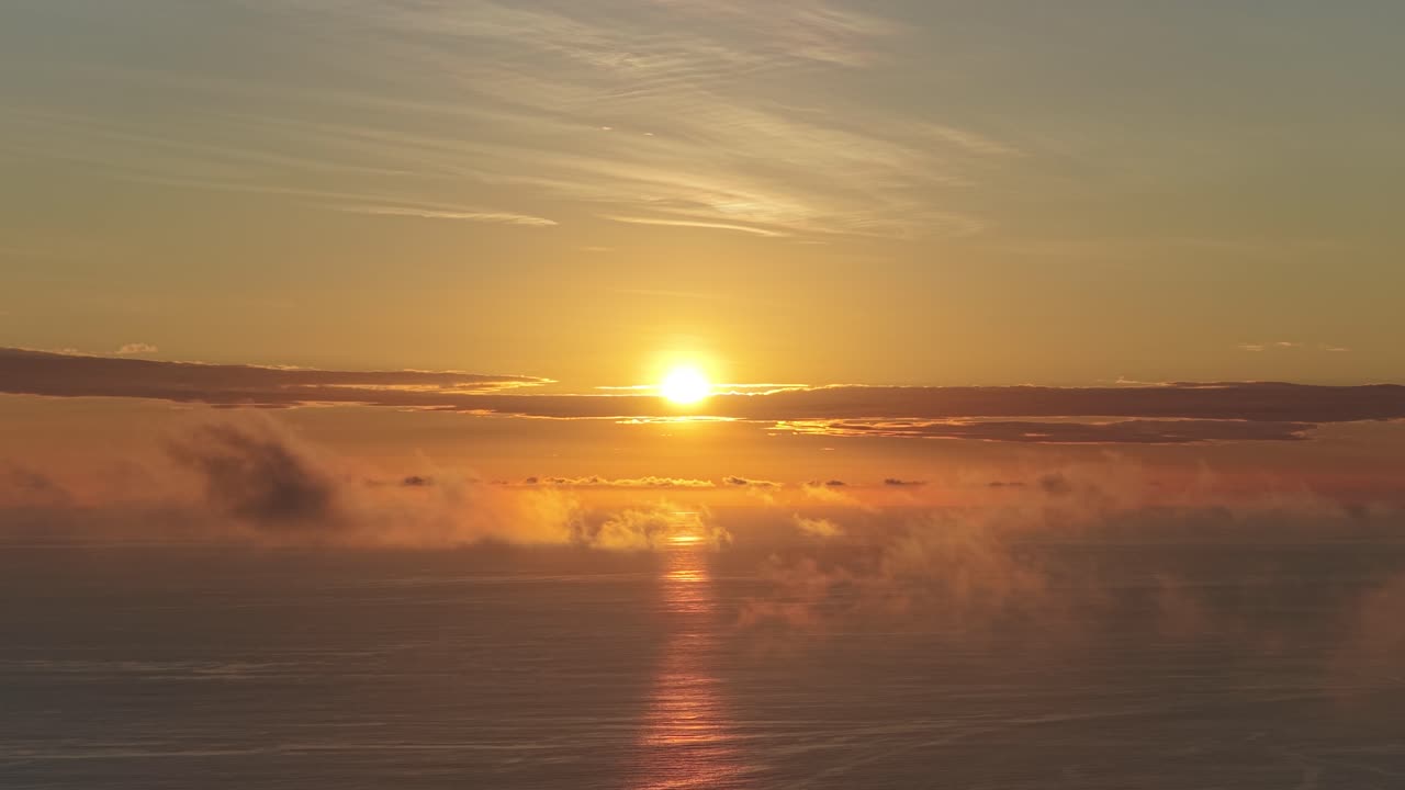 Goldener Sonnenuntergang über dem Meer mit Wolken und Wasserspiegelung