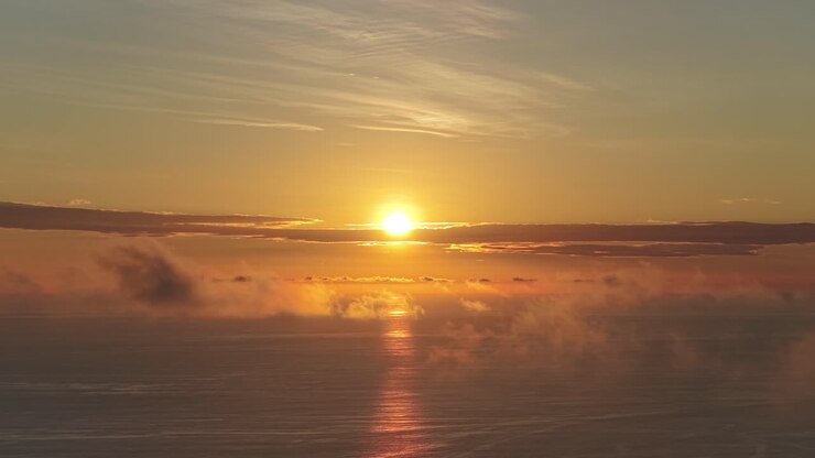 Tramonto dorato sull'oceano con nuvole e riflesso sull'acqua
