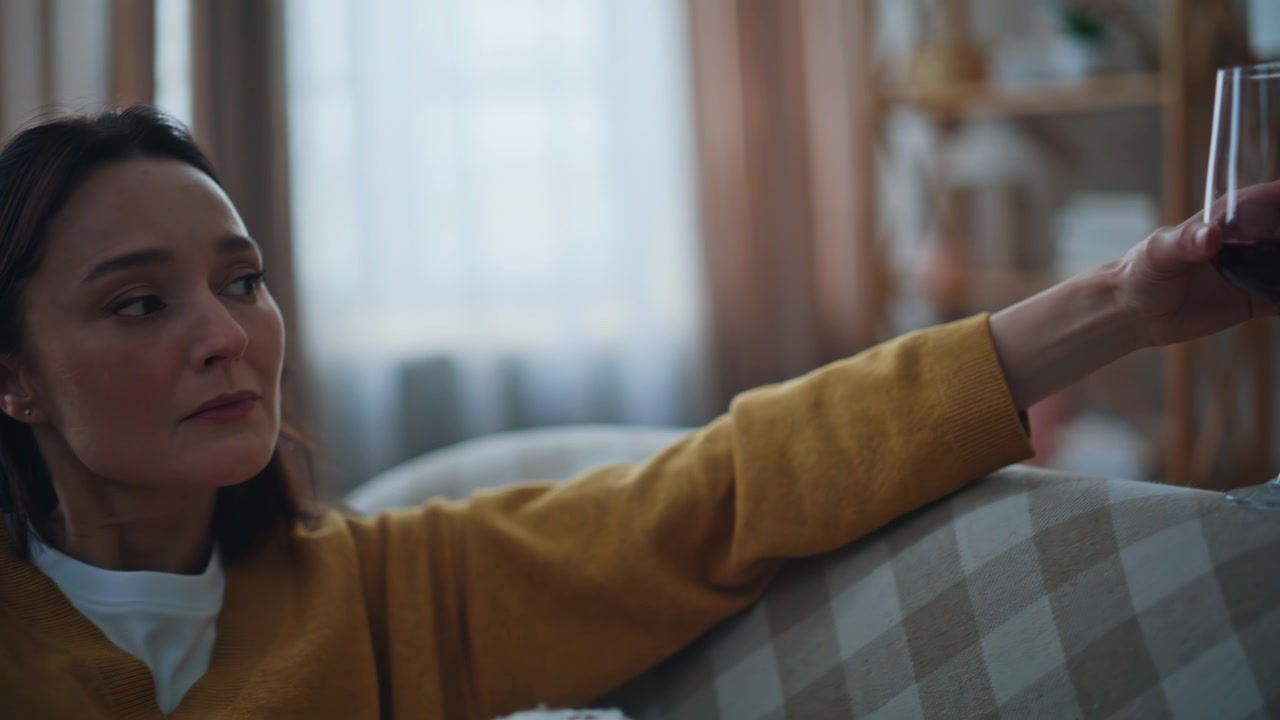 Lady hands holding wineglass in evening living room closeup. Depressed woman