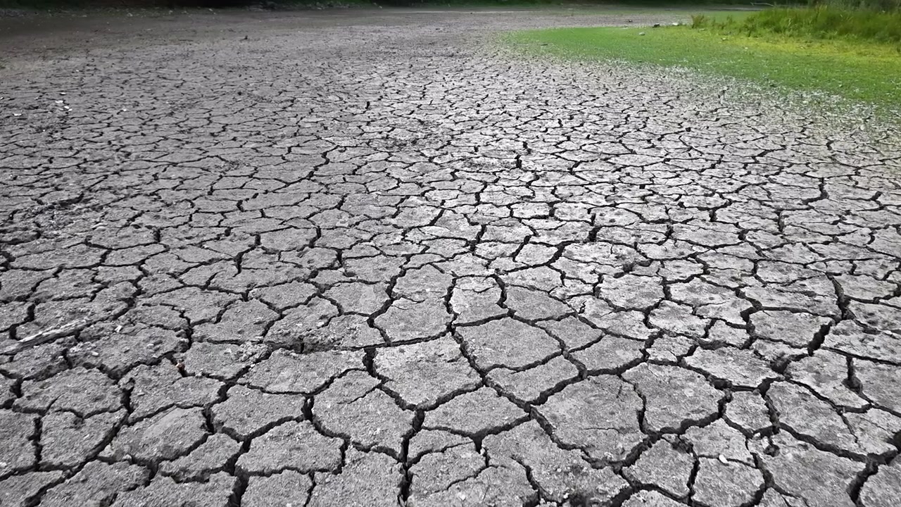 La superficie arida e screpolata di un letto di lago prosciugato illustra il grave impatto di una prolungata siccità regionale e del cambiamento climatico.