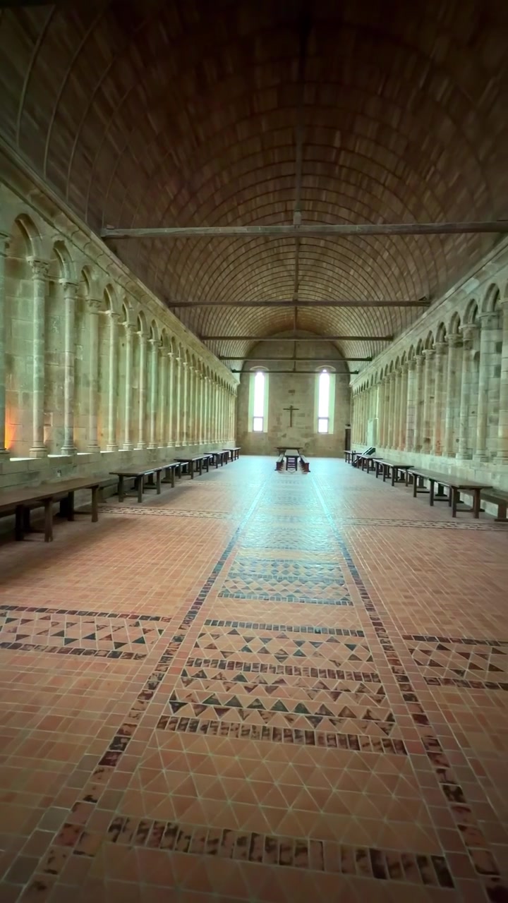 Ampia veduta che attraversa una sala medievale a volta con colonne in pietra e panche