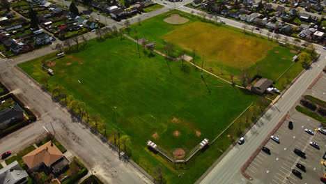 Vista-Aérea-Del-Campo-De-Fútbol-Y-La-Conducción-De-Automóviles-En-La-Ciudad-Durante-El-Día-En-Port-Alberni,-Isla-De-Vancouver,-Canadá