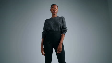 elegant woman posing in grey sweater and black pants