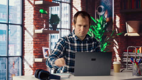 employee at workstation completing spreadsheets on laptop and listening music