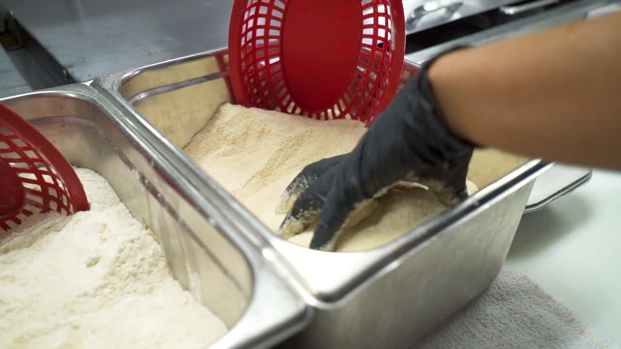 Chef batters seafood, cook coats seafood in breadcrumbs and cornmeal before frying, slow motion HD