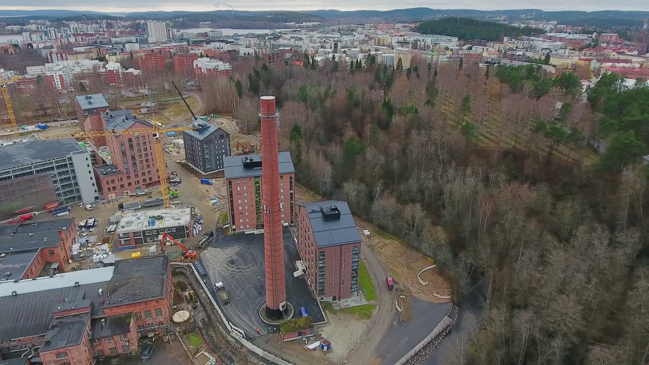 A drone shot of a factory chimney standing out among newly built homes