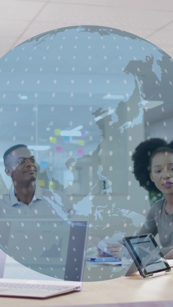 Vertical video: Man and woman studying rotating globe appearing over meeting, showing business maps