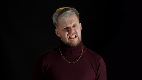 Disappointed-handsome-man-with-blue-eyes-showing-negative-and-agressive-emotion-on-black-background