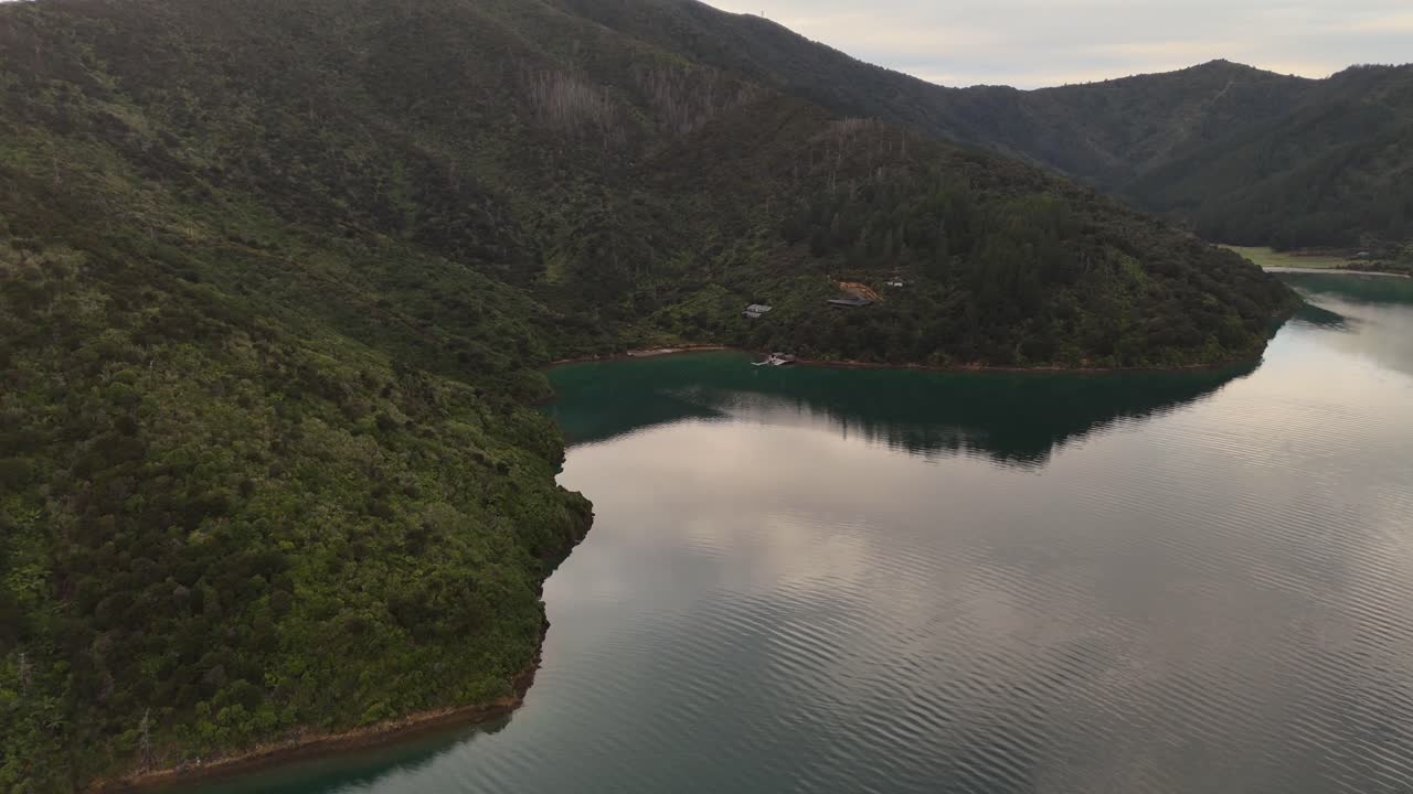 Breathtaking 4K drone footage captures a charming house fronting a serene lake, nestled between majestic mountains in the Picton area of New Zealand's South Island, showcasing peaceful natural beauty