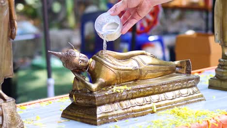 pouring water over buddha statue in ceremony