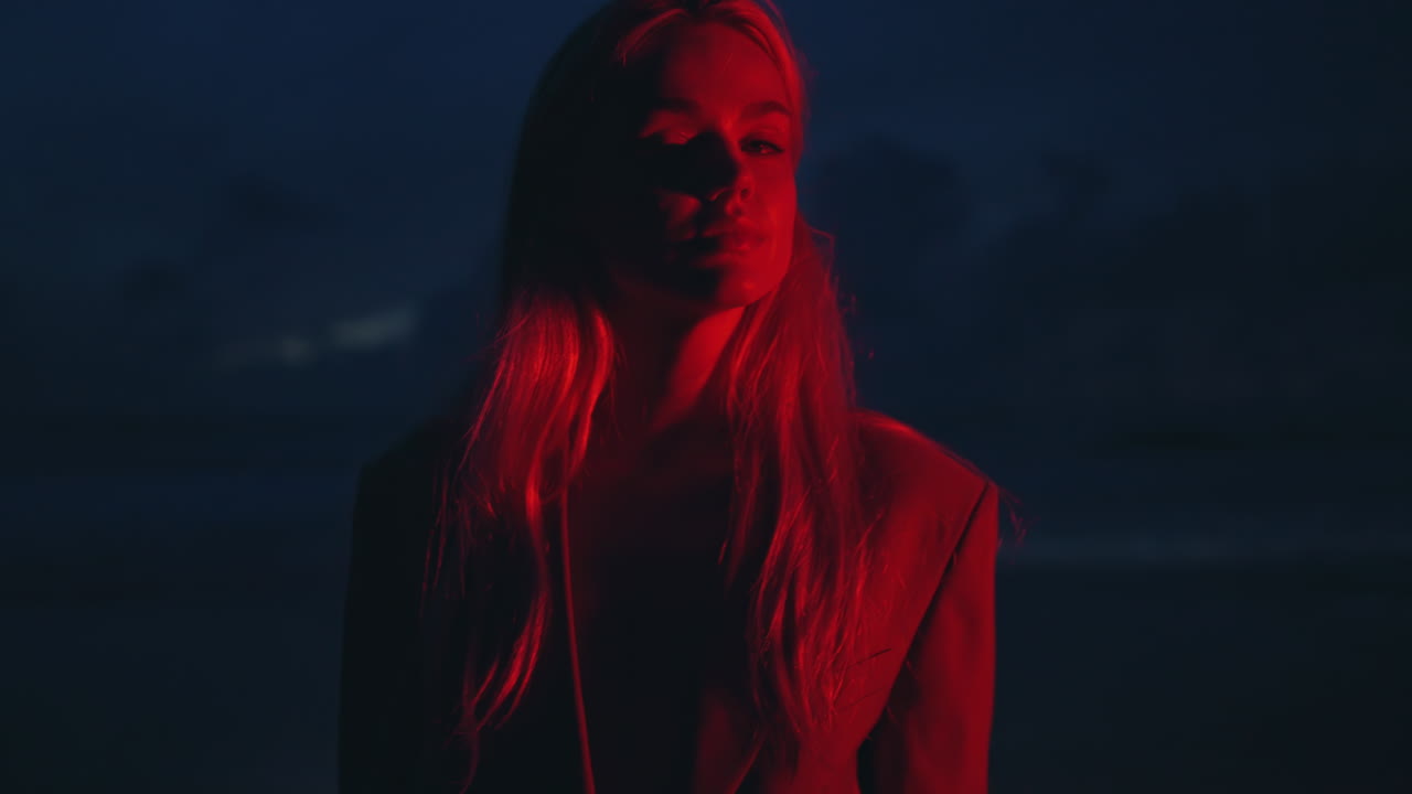 niña de neón roja mirando cámara de primer plano. joven atractiva girando caminando