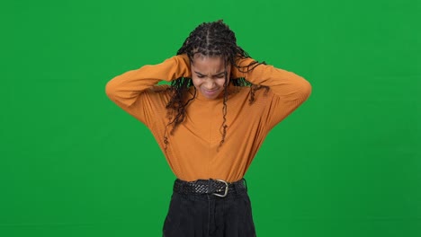 portrait of teen african american girl suffering from loud noise looking at camera shaking head no posing at chromakey background. unhappy frustrated teenager closing ears with hands on green screen.
