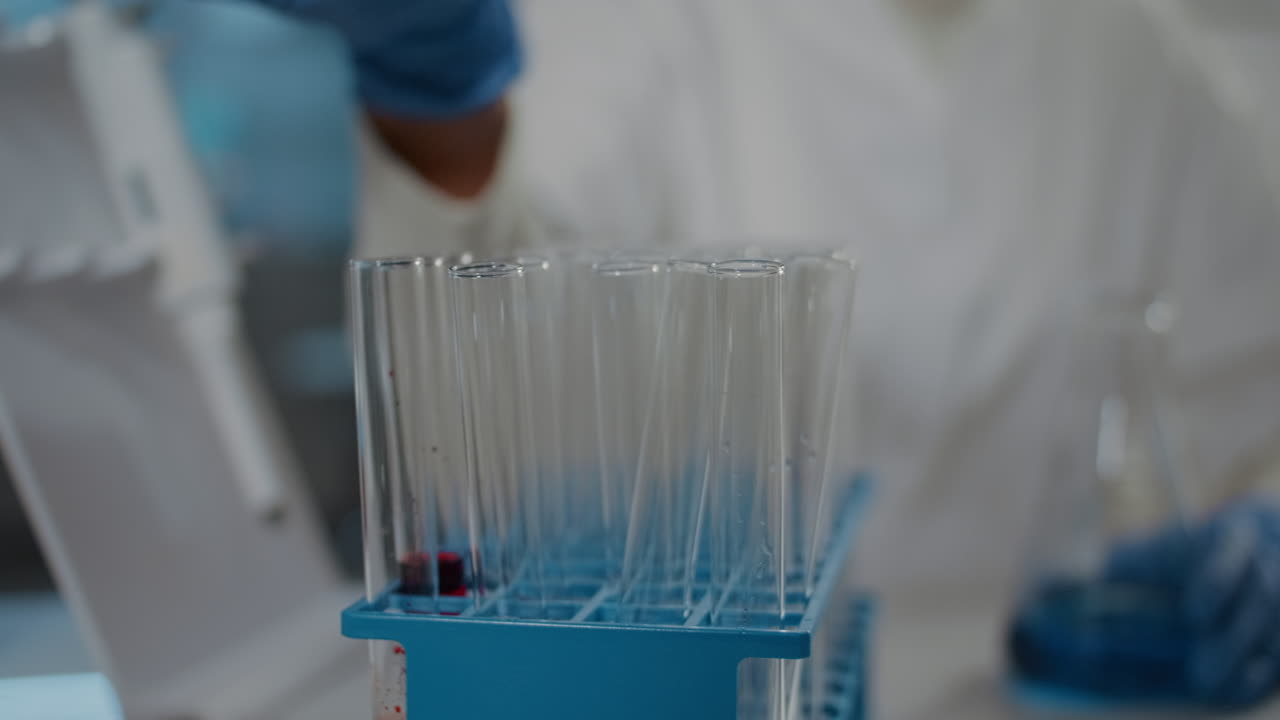 Specialist working with micro pipette to drop liquid in beaker