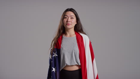 retrato de estudio de una mujer envuelta en la bandera estadounidense celebrando el 4 de julio, día de la independencia.