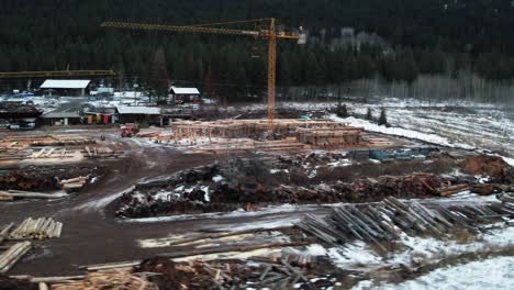 timber and technology: a crane assists in the construction of a log-home in the snowy forest of british columbia, canada