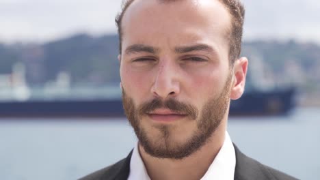 tired businessman looking at camera by the sea.